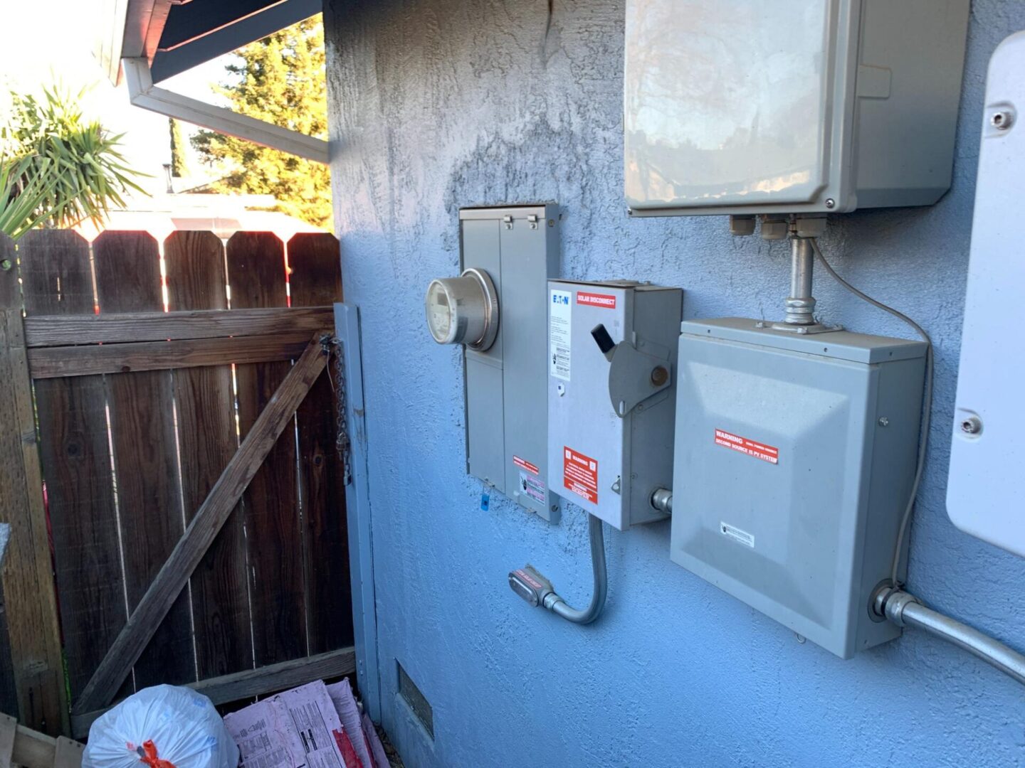 A blue wall with electrical boxes and wires.