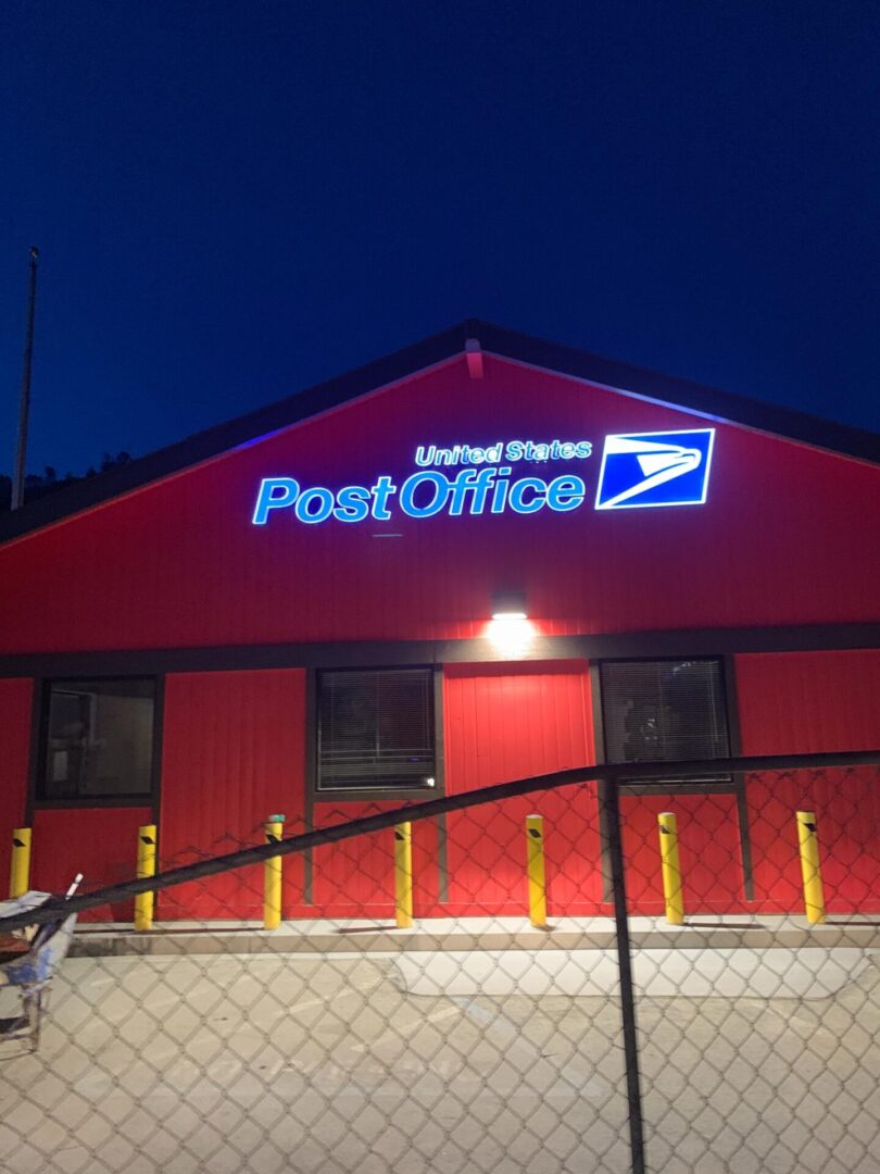 A red post office building with the lights on.