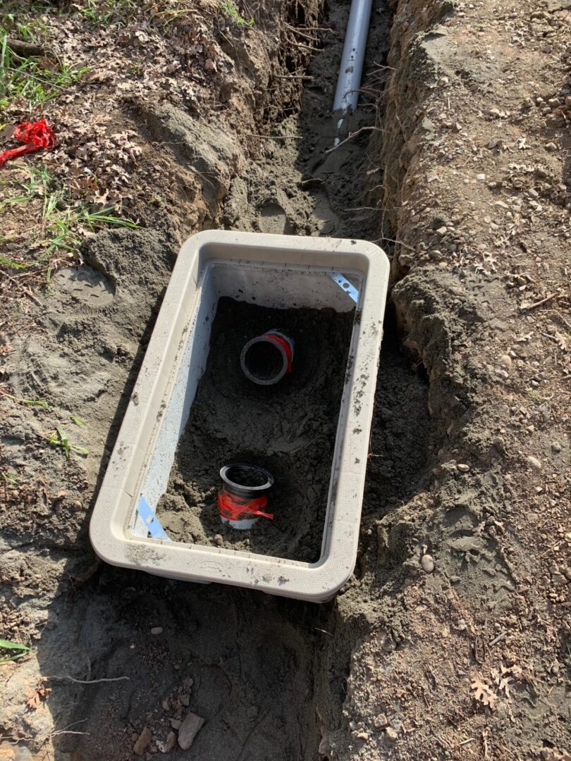 A white box with a red lid in the dirt.