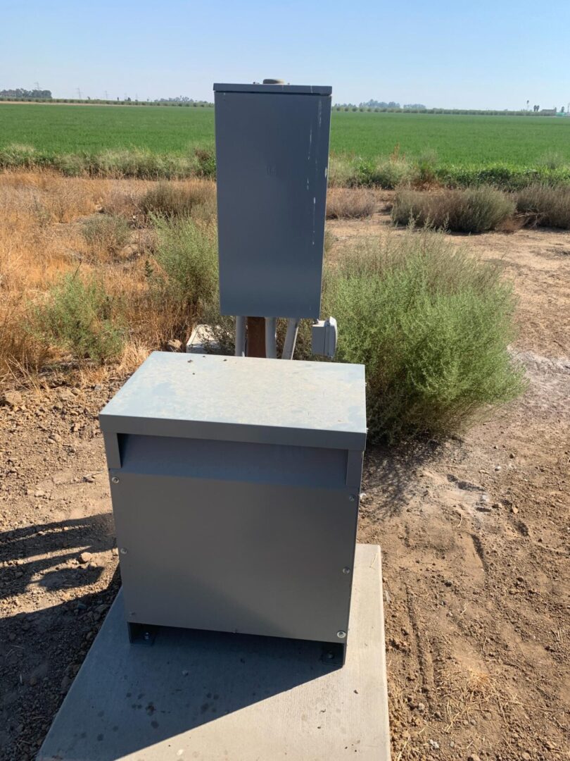 A metal box sitting in the middle of an open field.