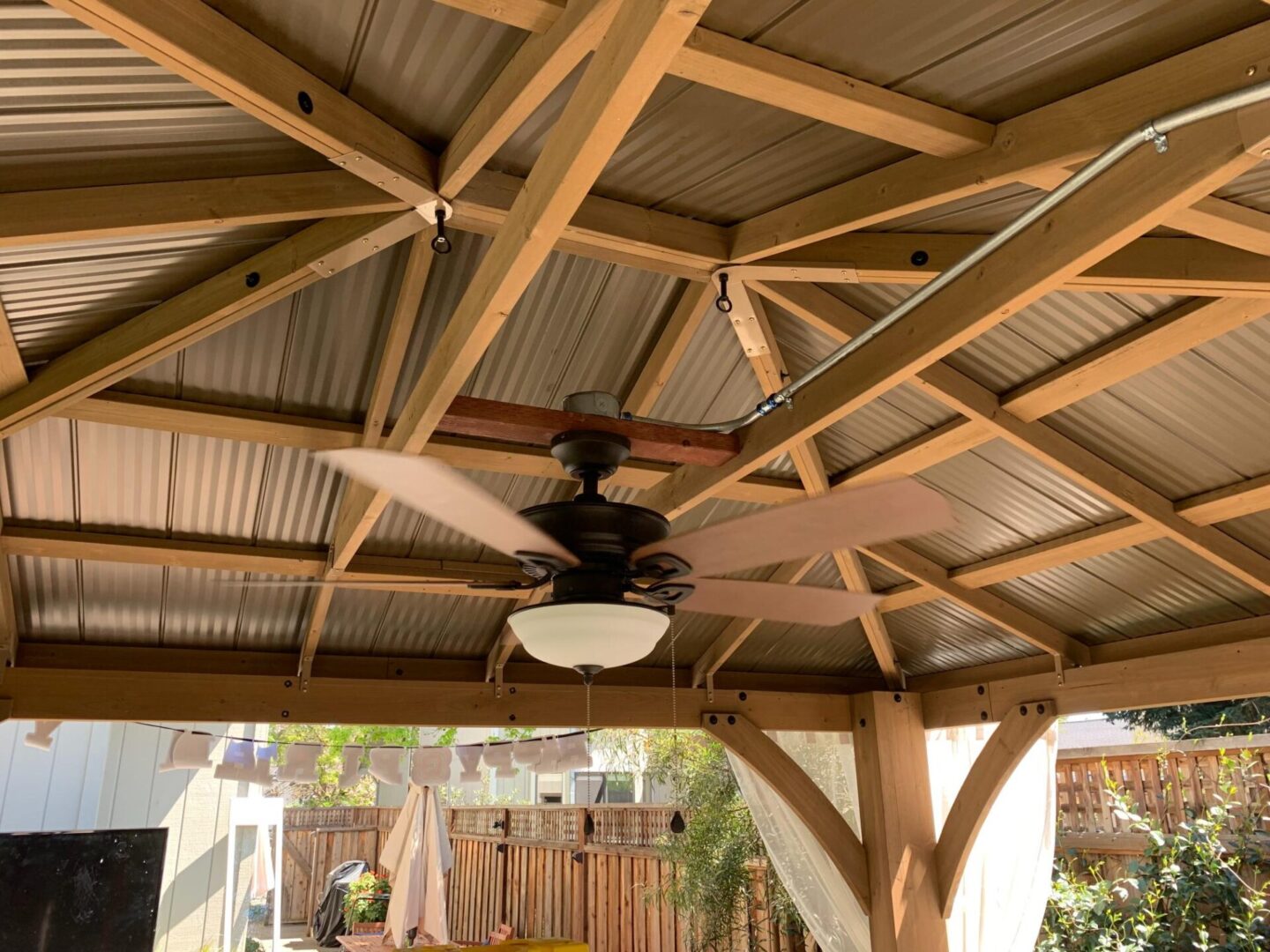 A ceiling fan in the middle of an outdoor patio.