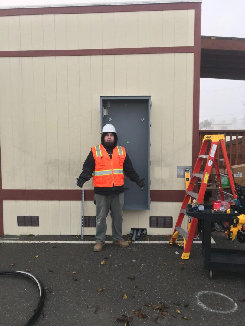 A man in an orange vest standing next to a door.