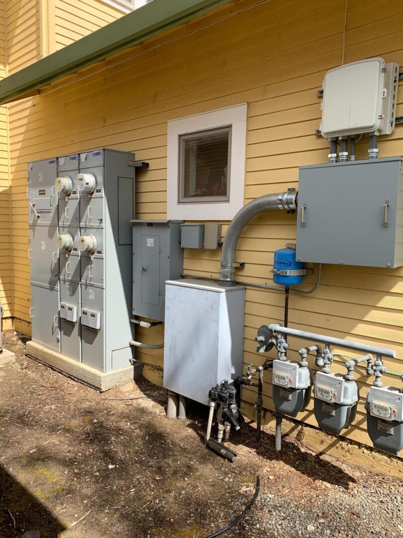 A yellow house with electrical boxes and wires.