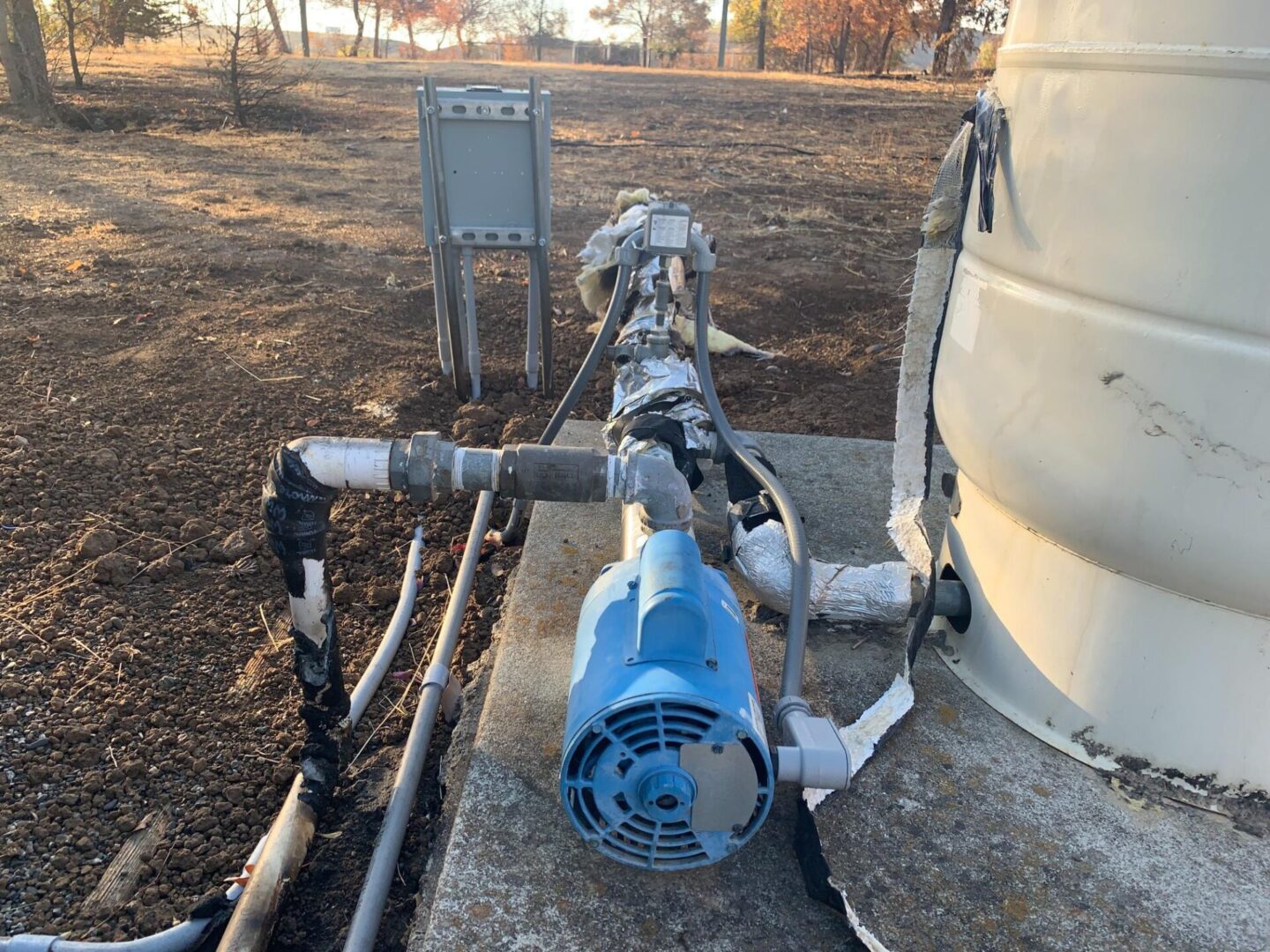 A blue water pump sitting on the side of a road.