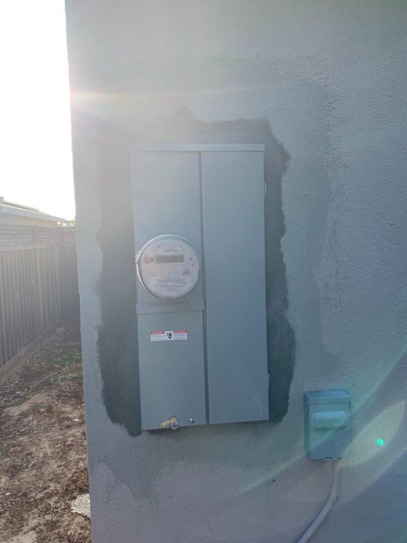 A gray electrical box on the side of a house.