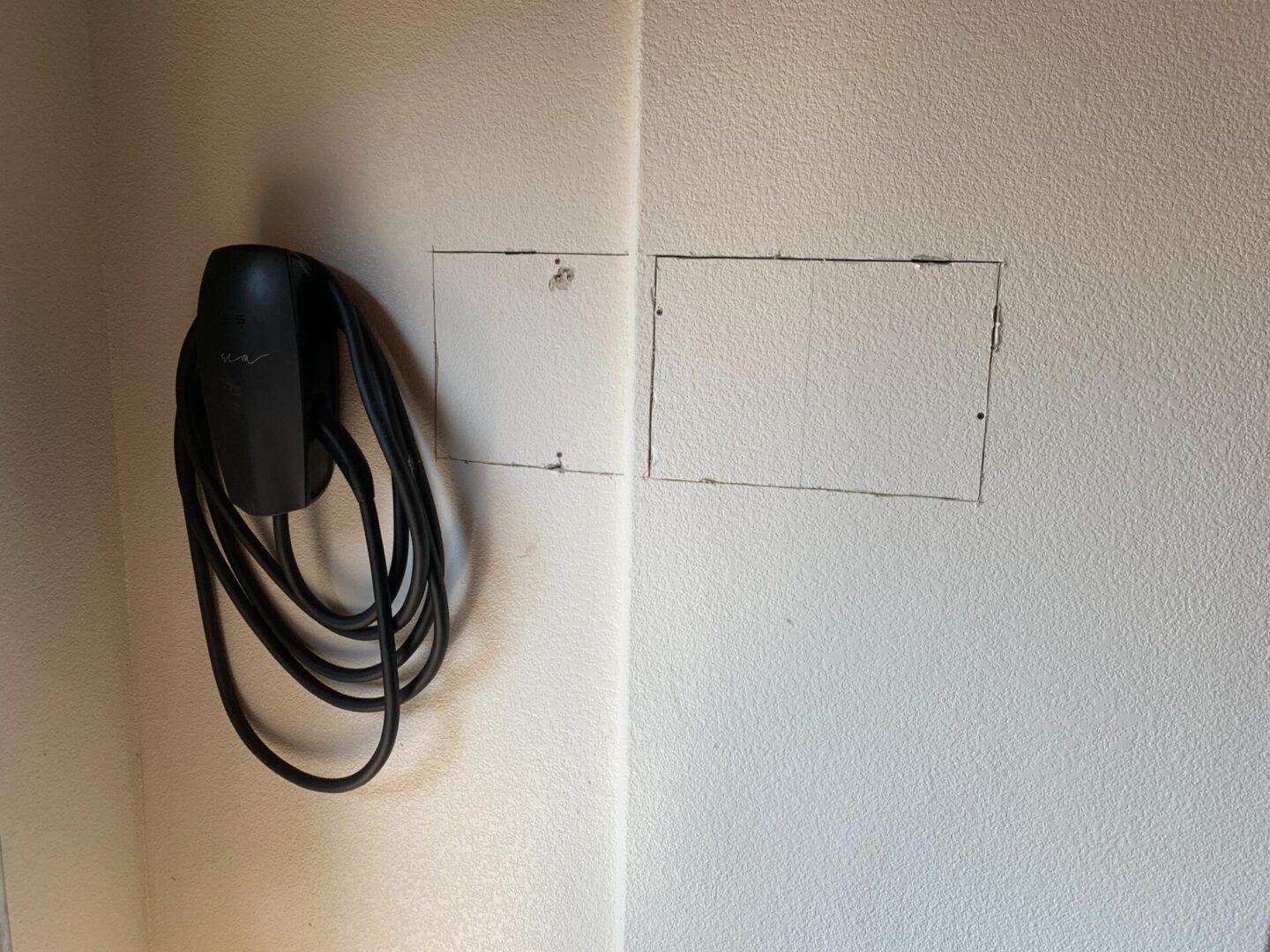 A wall mounted with a black cord and a white box