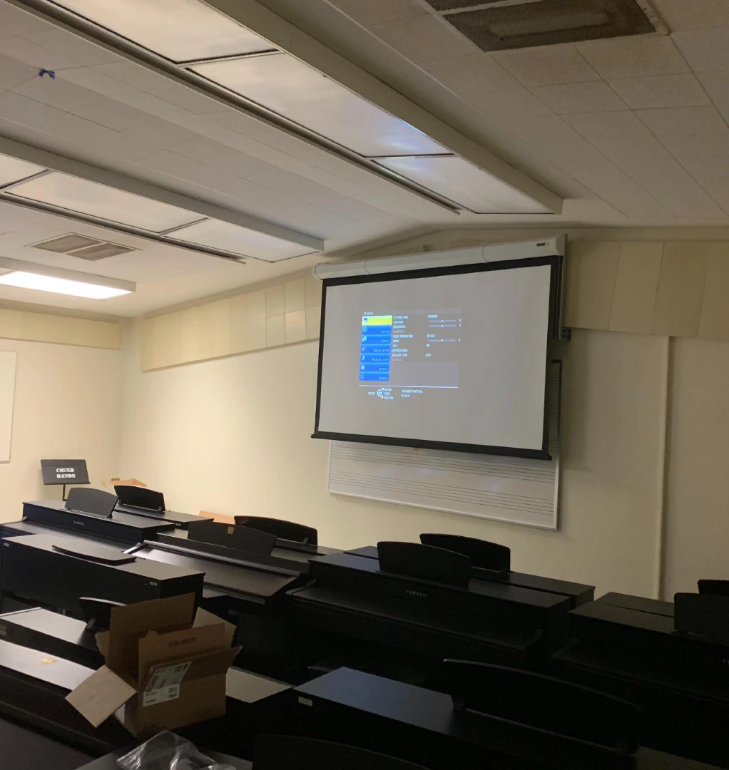 A large screen projector in the middle of an empty classroom.